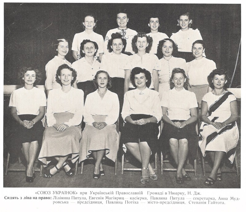 Photograph is undated, but is likely from 1948. The caption identifies those seated (left to right, in Library of Congress transliteration) as: Liliiana Pytula, Evheniia Mahiiarits (treasurer), Pavlyna Pytula (secretary), Anna Mudrovs'ka (president), Pavlyna Potikha (vice president), Stepania Haihota.